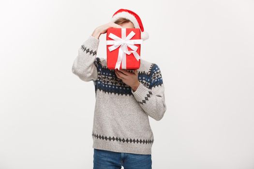 Holiday Concept - young handsome man hiding himself behind present.