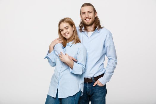 Portrait of cheerful young couple standing and hugging each other on isolated white background.