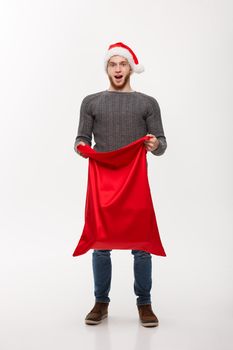 Christmas concept - Young beard handsome man exciting open santa big bag for present.