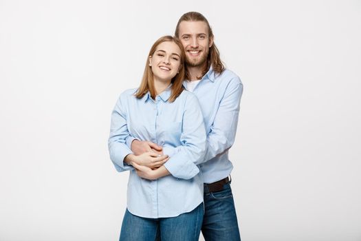 Portrait of cheerful young couple standing and hugging each other on isolated white background.