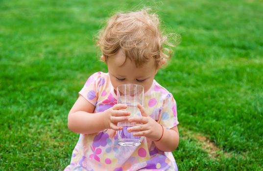 Baby drinks water from a glass. Selective focus. Child.