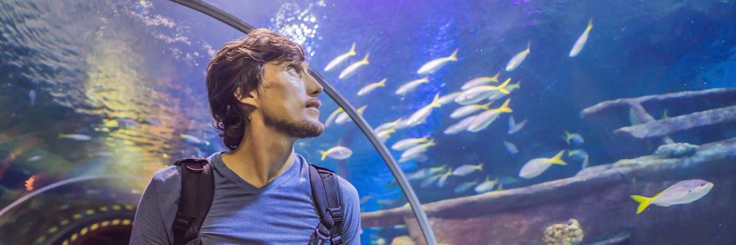 curious tourist watching with interest on shark in oceanarium tunnel. BANNER, LONG FORMAT