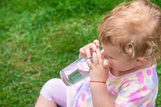 Baby drinks water from a glass. Selective focus. Child.