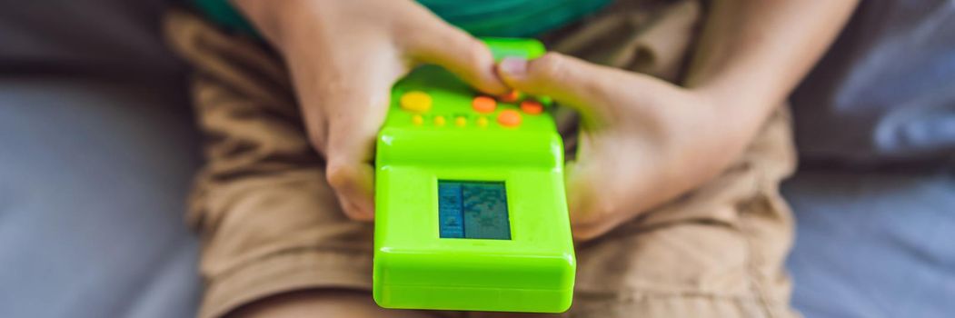 Young boy playing old school portable game console, electronic retro pocket toy with monochrome display. BANNER, LONG FORMAT