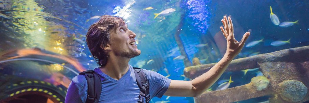 curious tourist watching with interest on shark in oceanarium tunnel. BANNER, LONG FORMAT