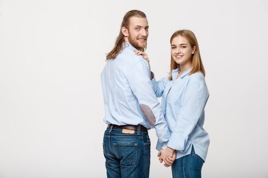 Portrait of cheerful young couple standing and hugging each other on isolated white background.