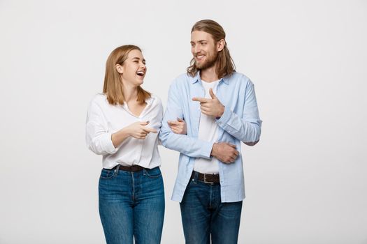 Portrait young happy couple love smiling embracing point finger to empty copy space, man and woman smile looking up, isolated over white background.