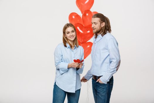 Young attactive caucasian couple holding heart balloon and paper