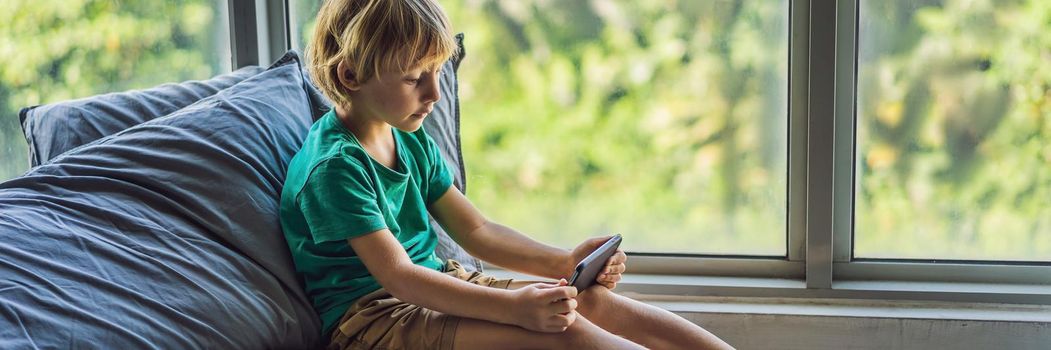 Little blond boy playing games on smartphone. BANNER, LONG FORMAT