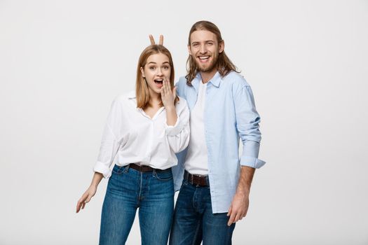 Portrait of lovely young couple showing peace or victory sign on white studio background.