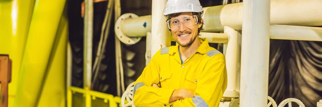 Young man in a yellow work uniform, glasses and helmet in industrial environment,oil Platform or liquefied gas plant. BANNER, LONG FORMAT