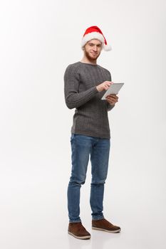 Holiday concept - Young beard handsome man working on digital tablet over white background.
