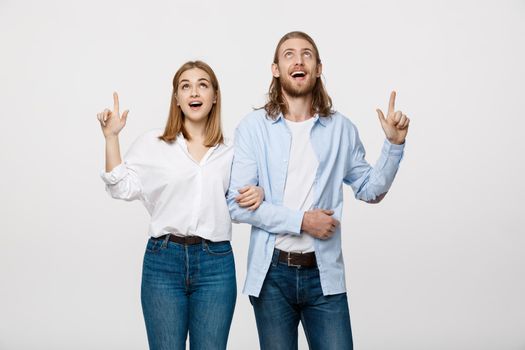 Portrait young happy couple love smiling embracing point finger to empty copy space, man and woman smile looking up, isolated over white background.