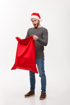 Christmas concept - Young beard handsome man exciting open santa big bag for present.