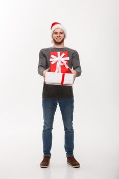 Christmas Concept - Happy young handsome man with beard giving presents to camera isolated on white background.