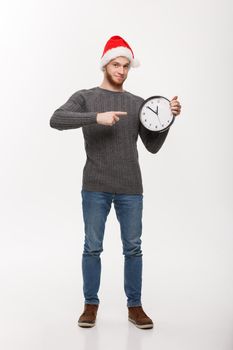 Holiday concept - Young handsome beard man pointing on white clock telling the time.