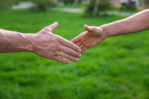 Handshake of men at a meeting in the park. Selective focus. People.