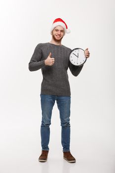 Holiday concept - Young handsome beard man thumb up on white clock.