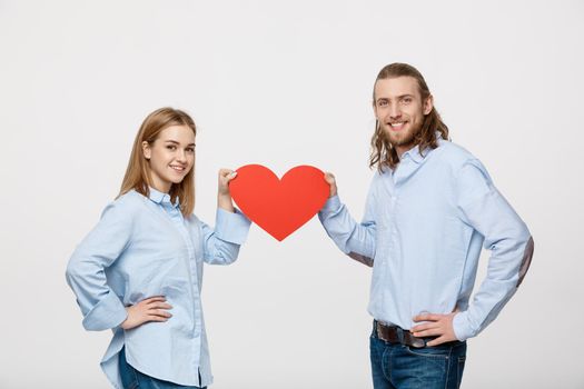 Portrait of young happy couple in love holding red paper heart