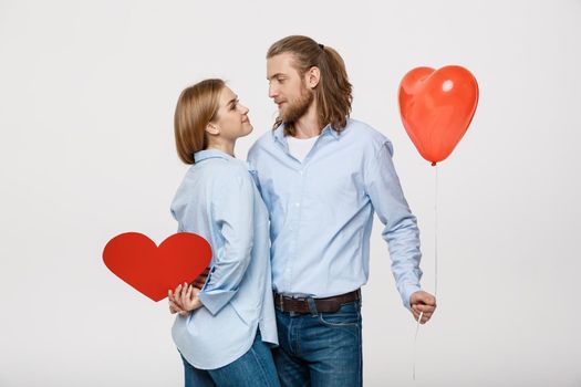 Portrait of young man and woman holding a heart- shaped balloon and paper.