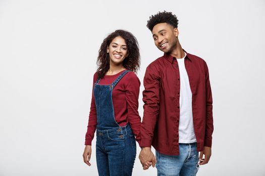 happy african american couple holding hands and looking back isolated on white.