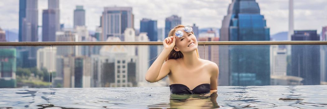 Young woman in outdoor swimming pool with city view in blue sky. Rich people. BANNER, LONG FORMAT