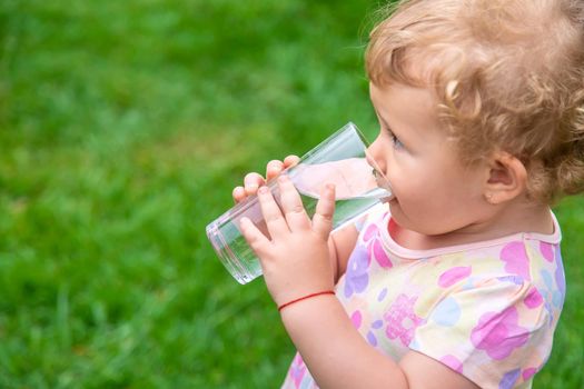 Baby drinks water from a glass. Selective focus. Child.