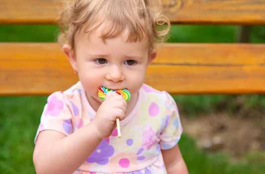 Baby eats a lollipop in the park. Selective focus. Child.