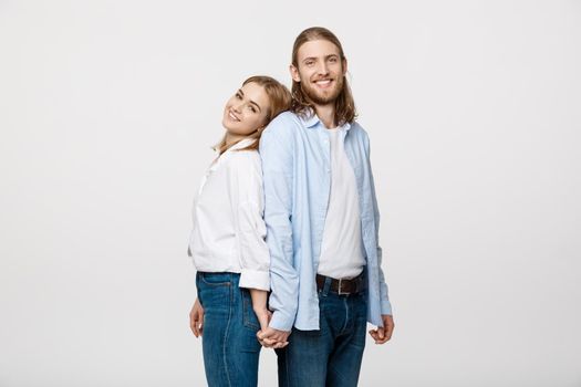 Cheerful happy man and woman with holding hands standing back to back