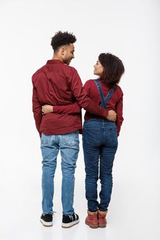 Full lenght back view of young African American couple hugging together isolated on white background.