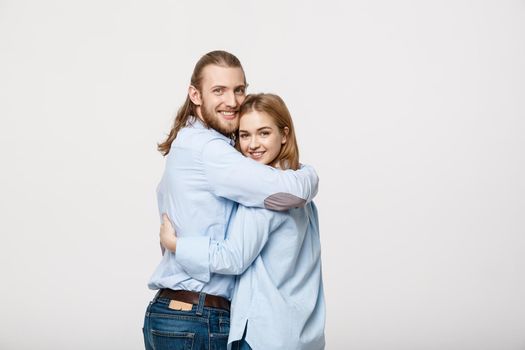 Portrait of cheerful young couple standing and hugging each other on isolated white background.