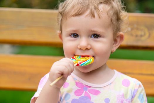 Baby eats a lollipop in the park. Selective focus. Child.