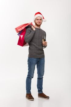 Christmas Concept - Young handsome beard man holding glass of champagne and shopping bags with happy facial expression.