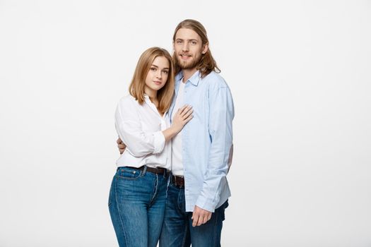 Portrait of cheerful young couple standing and hugging each other on isolated white background.