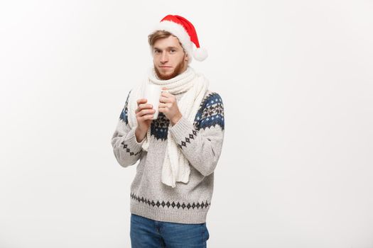 Christmas concept - Young beard man in sweater and santa hat holding a hot coffee cup isolated on white with copy space.