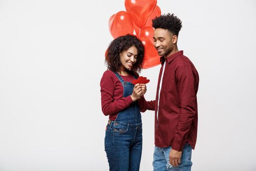 Portrait of young couple in love holding red paper heart and balloon