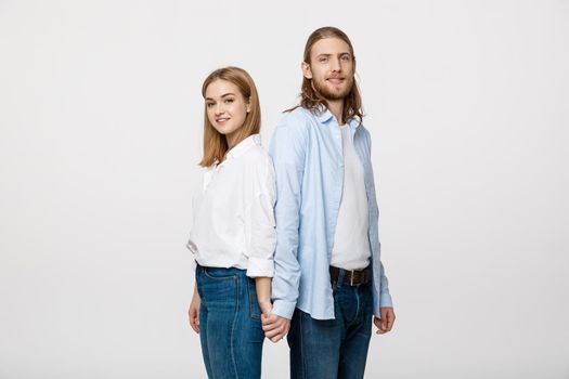 Cheerful happy man and woman with holding hands standing back to back