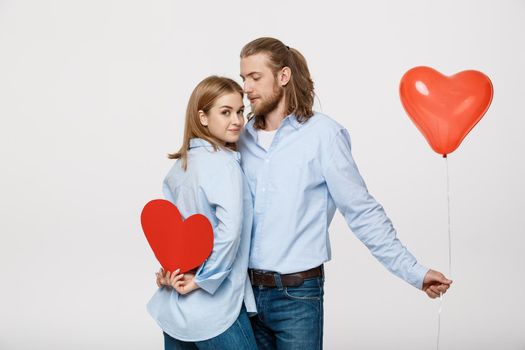 Young attactive caucasian couple holding heart balloon and paper