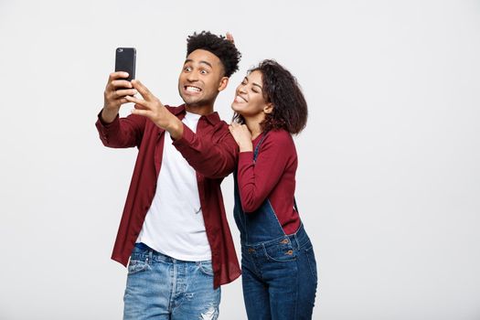 Young attractive African American Couple Pose For selfie pose with smart phone.