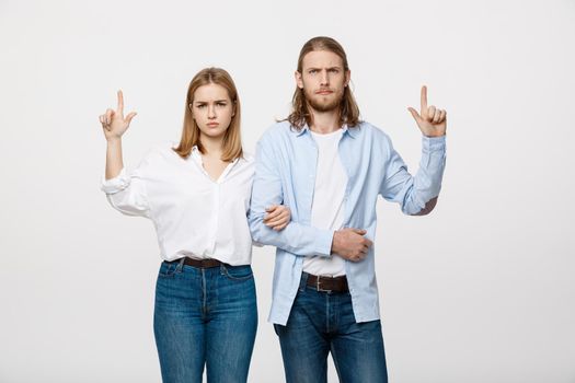 Portrait young happy couple love smiling embracing point finger to empty copy space, man and woman smile looking up, isolated over white background.