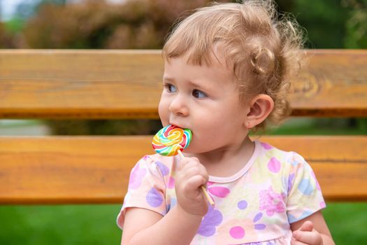 Baby eats a lollipop in the park. Selective focus. Child.