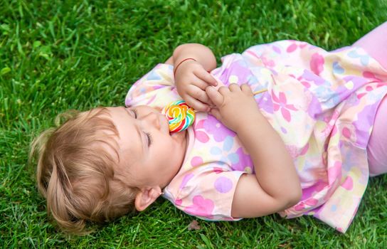 Baby eats a lollipop in the park. Selective focus. Child.