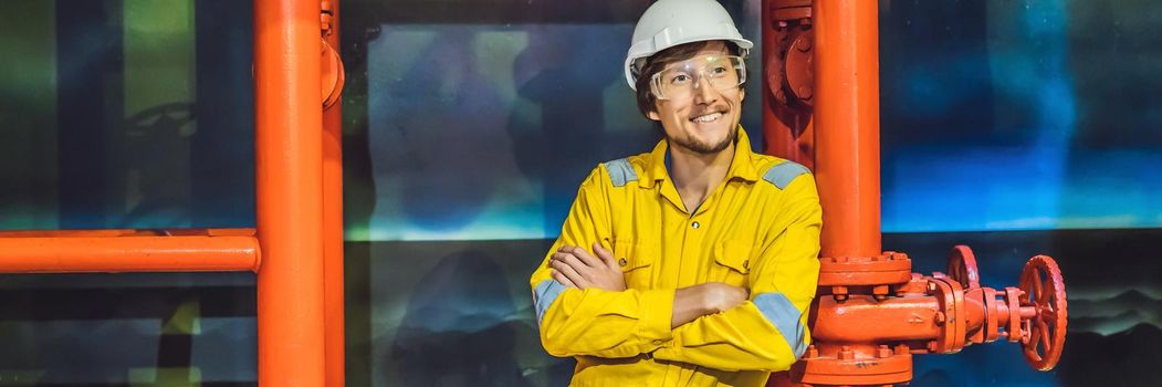 Young man in a yellow work uniform, glasses and helmet in industrial environment,oil Platform or liquefied gas plant. BANNER, LONG FORMAT