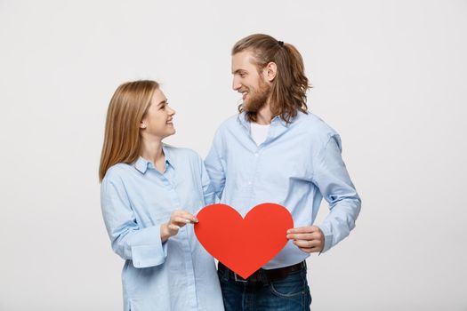Portrait of young happy couple in love holding red paper heart