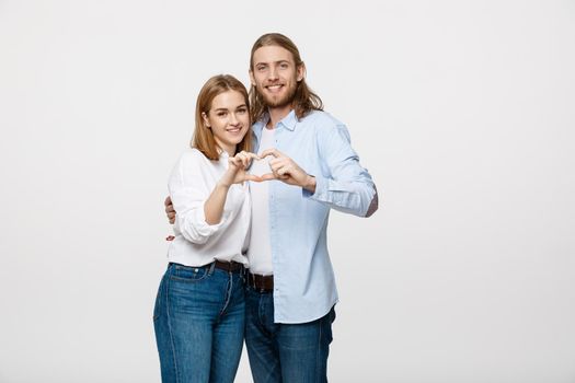 Valentine Couple - portrait of smiling Beauty Girl and her Handsome Boyfriend making shape of Heart by their Hands