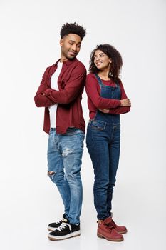 Cheerful African American man and woman with crossed hands standing back to back over isolated white background