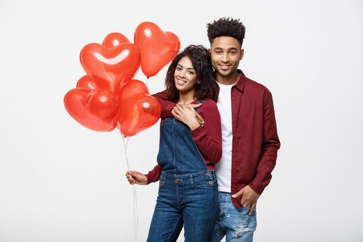 Close up attractive African American couple huging and holding red heart balloon