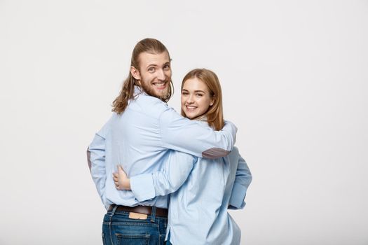 Portrait of cheerful young couple standing and hugging each other on isolated white background.