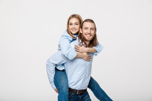 Portrait of smiling man giving happy woman a piggyback ride