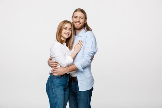 Portrait of cheerful young couple standing and hugging each other on isolated white background.